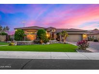 Beautiful single-story home with manicured lawn, stone accents, and tile roof at sunset at 9955 E Celtic Dr, Scottsdale, AZ 85260