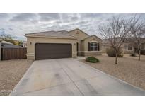 Tan home featuring a two-car garage, landscaped yard, and a neutral color palette at 10705 E Sunflower Ct, Florence, AZ 85132