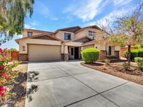 Two-story home with a large driveway and three-car garage, showcasing its well-maintained landscaping and exterior design at 18225 W Mackenzie Dr, Goodyear, AZ 85395