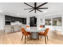 Modern kitchen area with stainless steel appliances, stylish island, light wood floors, and a dining table with orange chairs at 2920 S Bala Dr, Tempe, AZ 85282