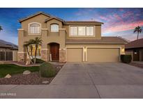 Two-story tan home with a three-car garage, stone accents and beautiful desert landscaping at 3017 S Mesita --, Mesa, AZ 85212