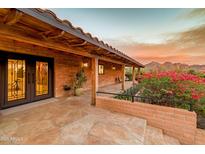 Inviting covered front porch featuring flagstone flooring, brick accents, and lush landscaping with mountain views at 6845 N Hillside Dr, Paradise Valley, AZ 85253