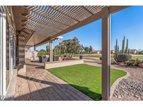 Inviting covered patio overlooking a green lawn and golf course with desert landscaping and comfortable seating at 15701 W Huron Dr, Sun City West, AZ 85375