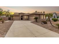 Charming home with a spacious driveway and desert landscaping featuring palm trees and stone accents at 4159 E Shannon St, Gilbert, AZ 85295