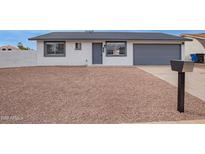 Charming single-story home with desert landscaping and a gray two-car garage door at 702 N Evergreen St, Gilbert, AZ 85233