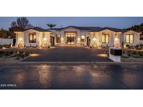 Stunning home exterior with a dark-paved driveway, desert landscaping, and inviting lighting at 7120 E Paradise Ranch Rd, Paradise Valley, AZ 85253