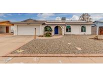 Charming home featuring a blue accent trim, solar panels, and a low-maintenance rock yard at 627 W Flower Ave, Mesa, AZ 85210