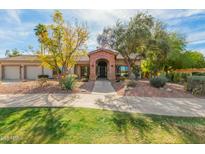 Charming single-story home with a brick archway entry, desert landscaping, and a lush green lawn at 8005 N Via De Lago --, Scottsdale, AZ 85258