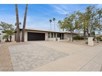 Attractive home exterior with manicured lawn, large driveway and palm trees at 8709 E Mackenzie Dr, Scottsdale, AZ 85251