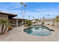 Backyard showcasing a sparkling pool, patio furniture, and lush landscaping with palm trees at 8709 E Mackenzie Dr, Scottsdale, AZ 85251