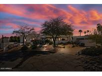 Stunning desert home with mature landscaping and a vibrant sunset sky backdrop at 9331 E La Posada Ct, Scottsdale, AZ 85255