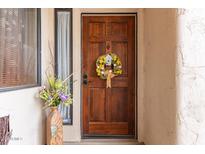 Charming wooden front door adorned with a decorative wreath and a vibrant vase of flowers nearby at 9345 N 92Nd St # 201, Scottsdale, AZ 85258