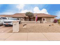 Charming single-story home featuring a tile roof, desert landscaping, and an American flag at 13602 W Ballad Dr, Sun City West, AZ 85375