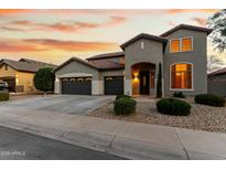 Charming two-story home with a three-car garage and beautifully landscaped front yard against a colorful sunset sky at 4429 W Paseo Way, Laveen, AZ 85339