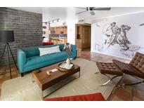 Stylish living room boasts a modern teal couch, rustic brick wall, and access to the kitchen area at 7740 E Heatherbrae Ave # 5, Scottsdale, AZ 85251
