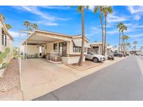 Inviting mobile home featuring a carport, front porch, and well-maintained landscaping with palm trees at 1152 S Sioux Dr, Apache Junction, AZ 85119