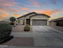 Charming single-story home featuring neutral stucco, complemented by a well-maintained, low maintenance landscaped front yard at 17542 W Pinnacle Vista Dr, Surprise, AZ 85387