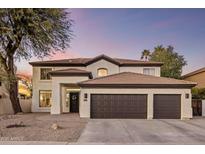 Beautiful two-story home with a three-car garage and a well-manicured front yard at dusk at 5210 E Danbury Rd, Scottsdale, AZ 85254