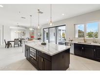 This is an open-concept kitchen with a large island, stainless steel appliances, and pendant lighting at 12201 N 66Th St, Scottsdale, AZ 85254