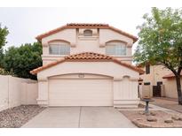 Beige two-story home featuring a red tile roof, concrete driveway, and an attached two-car garage at 909 W San Mateo Ct, Gilbert, AZ 85233