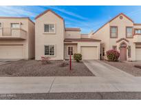 Beige two-story townhome featuring a front-facing garage and low-maintenance gravel landscaping at 1018 W Libra Dr, Tempe, AZ 85283
