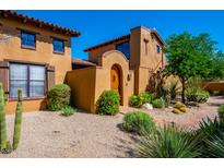 Charming Southwestern-style home showcasing a custom wooden door and lush desert landscaping at 10597 E Rising Sun Dr, Scottsdale, AZ 85262