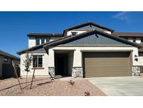 Two-story home featuring a two-car garage, stone accents, and a well-manicured yard under a clear blue sky at 25330 W Bowker St, Buckeye, AZ 85326
