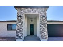 Inviting front entrance with stone accents, modern lighting, and a stylish black door at 11612 S 211Th Ln, Buckeye, AZ 85326