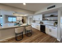 Bright, renovated kitchen features white cabinetry, an island with bar seating, and a wine cooler at 4524 W Larkspur Dr, Glendale, AZ 85304