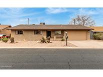 Charming single-story brick home with a two car garage and desert landscaping at 6917 E Flossmoor Ave, Mesa, AZ 85208