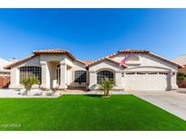 Beautiful single-story home with well-kept landscaping, an American flag, and a two car garage at 7849 W Kristal Way, Glendale, AZ 85308