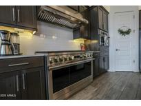 Modern kitchen with stainless steel appliances, dark cabinets, and white subway tile backsplash at 12519 W Oyer Ln, Peoria, AZ 85383