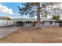 Charming single-story home featuring a carport, covered front porch and mature landscaping at 1925 W Wood Dr, Phoenix, AZ 85029