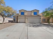 Beige two-story home with dormer windows and three-car garage, landscaped with desert plants and gravel at 19603 N Toya St, Maricopa, AZ 85138