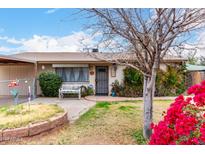 Charming single-story home featuring lush landscaping, a cozy bench, and secure gated access to the carport at 4202 N 74Th Dr, Phoenix, AZ 85033