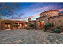 Stunning Tuscan-style home with a stone facade, arched entryway, and a meticulously paved circular driveway at 42613 N 111Th Pl, Scottsdale, AZ 85262