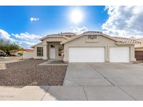 Charming beige home featuring a three-car garage, low-maintenance landscaping and concrete driveway at 5145 W Tonto Rd, Glendale, AZ 85308