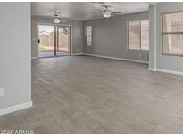 Spacious living room features wood-look floors, neutral paint, sliding glass doors, and ample natural light at 9734 W Carol Ave, Peoria, AZ 85345