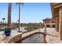 Picturesque backyard with spa, lake view, and tiled patio area, surrounded by lush landscaping at 10243 N 103Rd St, Scottsdale, AZ 85258