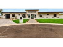 Modern home featuring a stone facade, black-framed windows, well-manicured lawn, and a brick pathway at 12240 N 62Nd Pl, Scottsdale, AZ 85254