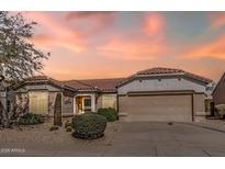 Charming single-story home featuring a tile roof, desert landscaping, and a two-car garage, all under a beautiful sunset at 14314 W Pecos Ln, Sun City West, AZ 85375