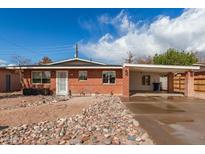 Inviting single-story brick home with a covered carport and distinctive rock landscape design in the front yard at 1512 W Fairmont Dr, Tempe, AZ 85282