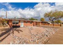 Charming single-story brick home featuring a covered carport and unique rock landscaping in the front yard at 1512 W Fairmont Dr, Tempe, AZ 85282