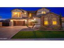 Elegant home features a stone facade, balcony, manicured lawn, brick driveway, and a two-car garage at 2448 E Amber Ct, Gilbert, AZ 85296