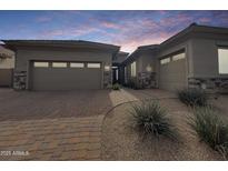 Beautiful home exterior featuring a three car garage, stone accents, desert landscaping, and a brick paver walkway at 6039 E Sienna Bouquet Pl, Cave Creek, AZ 85331