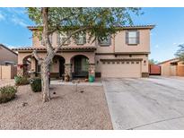 Charming two-story home featuring a two-car garage and inviting front porch with stone pillars and a decorative tree at 6208 N 78Th Dr, Glendale, AZ 85303