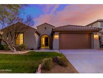 Charming single-Gathering home features a well-manicured lawn, neutral stucco, and a two-car garage at 9035 W Quail Track Dr, Peoria, AZ 85383