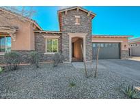 Charming single-story home featuring a stone facade, inviting entry gate, and attached two-car garage at 10039 W Jasmine Trl, Peoria, AZ 85383
