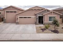 Charming single-story home showcasing a three-car garage, stone accents, and desert landscaping at 24757 N 175 Dr, Surprise, AZ 85387