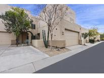 Inviting townhome featuring a two-car garage, desert landscaping, and a cozy front porch at 9065 E Gary Rd # 121, Scottsdale, AZ 85260